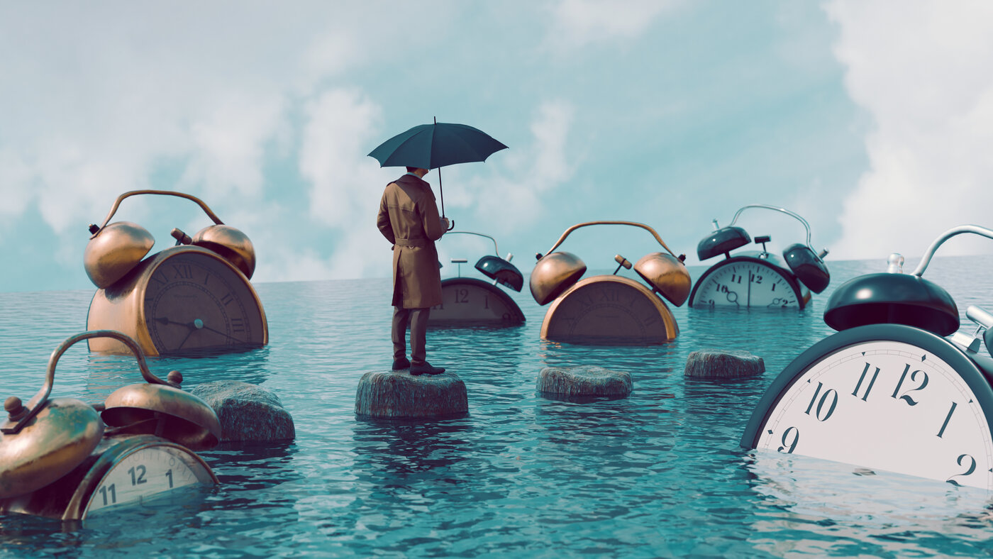 A man standing on rocks in water, surrounded by clocks